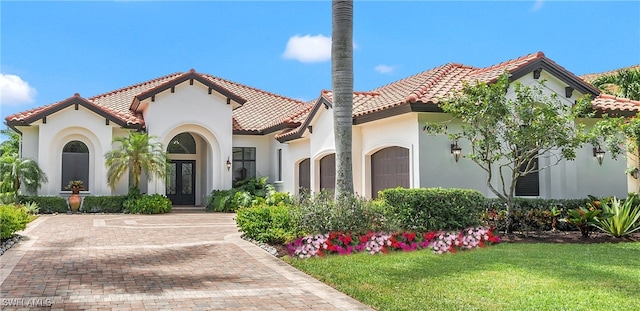 mediterranean / spanish-style house featuring a garage and a front lawn