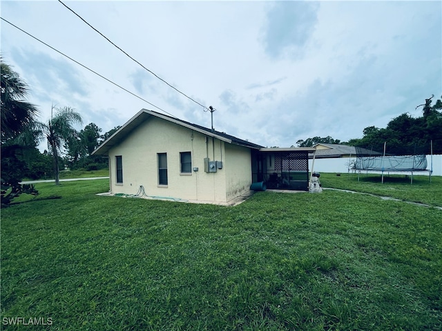 view of side of property with a lawn and a trampoline