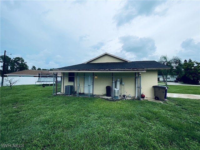 back of property featuring central AC and a lawn