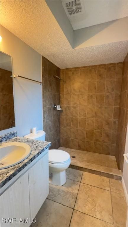 2807 E 8th St, Lehigh Acres, FL 33972 - full bath featuring vanity, a tile shower, toilet, a textured ceiling, and tile patterned floors
