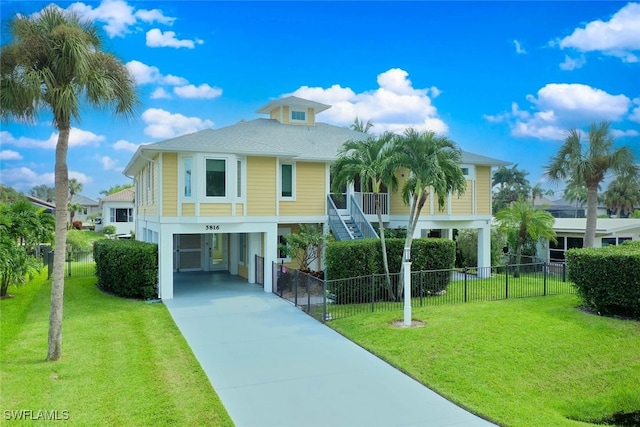 coastal inspired home featuring a front lawn and a carport