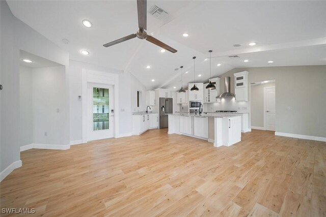 kitchen featuring light wood finished floors, stainless steel appliances, light countertops, visible vents, and wall chimney exhaust hood