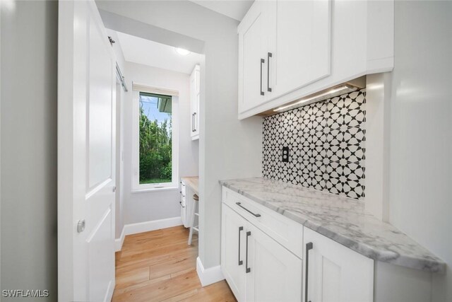 bar with light wood-type flooring, baseboards, and decorative backsplash