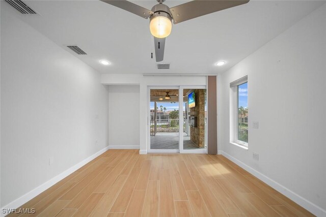 unfurnished room with light wood-style floors, visible vents, and baseboards