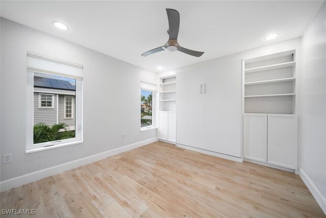 unfurnished room featuring ceiling fan, light hardwood / wood-style flooring, and built in features