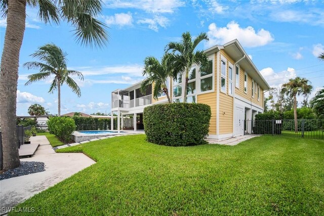 view of home's exterior featuring a lawn, fence, a sunroom, and a fenced in pool