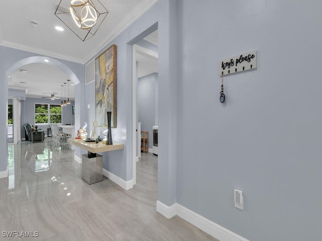 foyer with arched walkways, marble finish floor, crown molding, ceiling fan, and baseboards