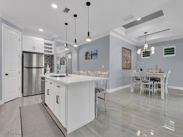 kitchen featuring stainless steel appliances, light countertops, a kitchen island with sink, a sink, and white cabinetry