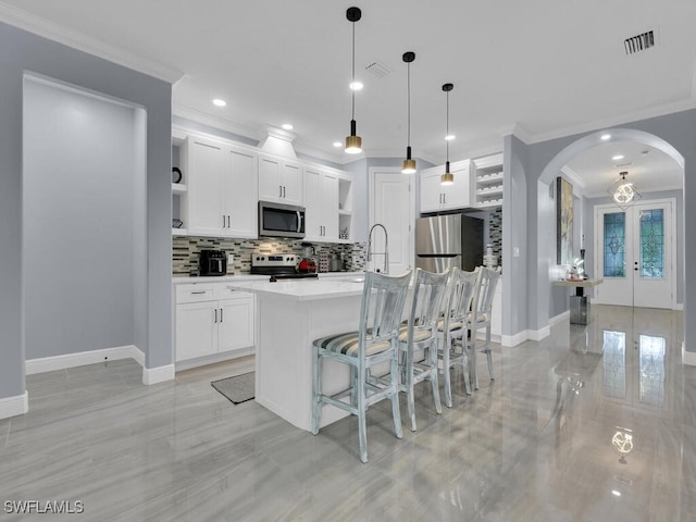 kitchen featuring pendant lighting, open shelves, light countertops, appliances with stainless steel finishes, and white cabinetry