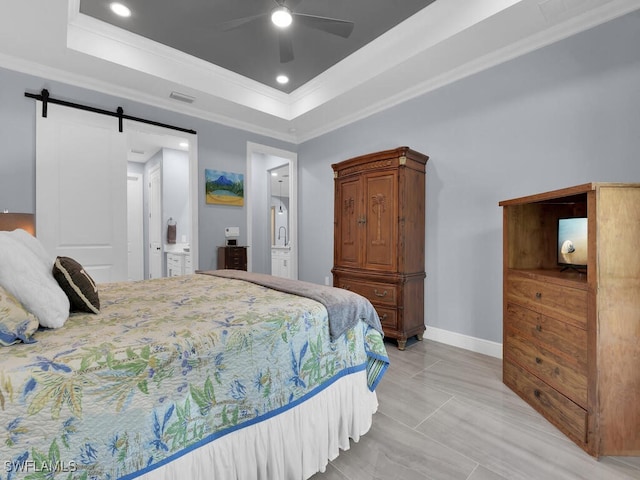 bedroom with ornamental molding, a tray ceiling, and a barn door