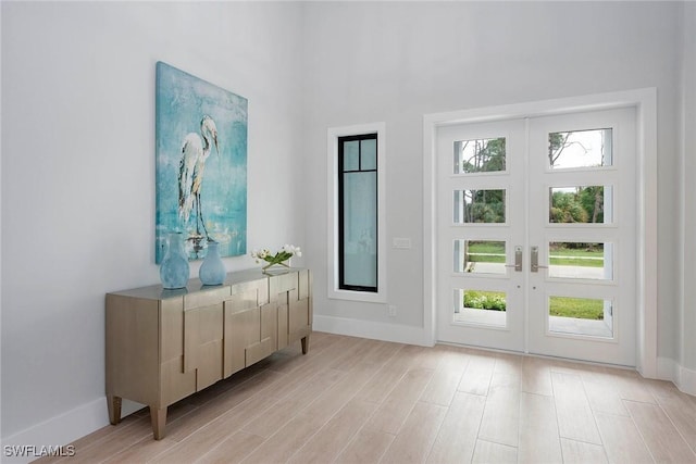 doorway with a healthy amount of sunlight, light wood-style floors, french doors, and baseboards