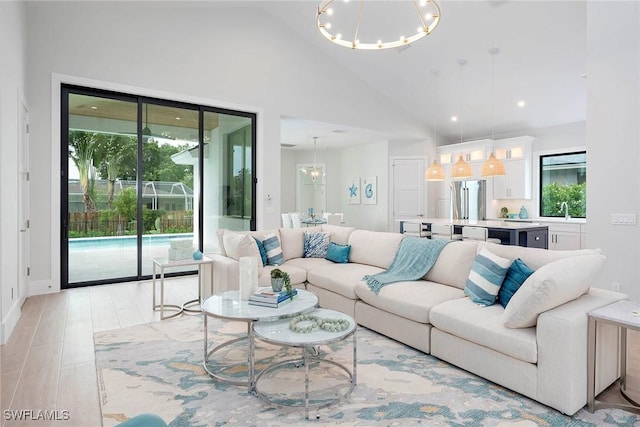 living area with recessed lighting, high vaulted ceiling, light wood-style floors, and an inviting chandelier