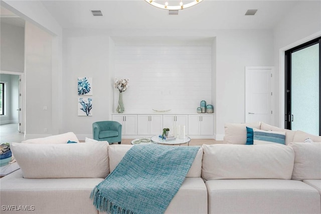 living room featuring visible vents, baseboards, and light wood finished floors