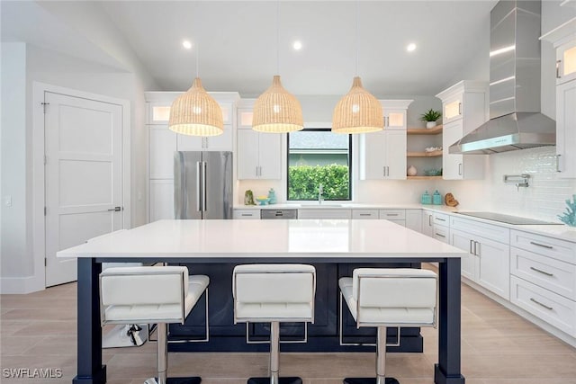 kitchen featuring glass insert cabinets, wall chimney range hood, decorative backsplash, stainless steel appliances, and white cabinetry