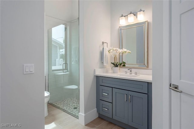 bathroom with baseboards, toilet, a stall shower, and vanity