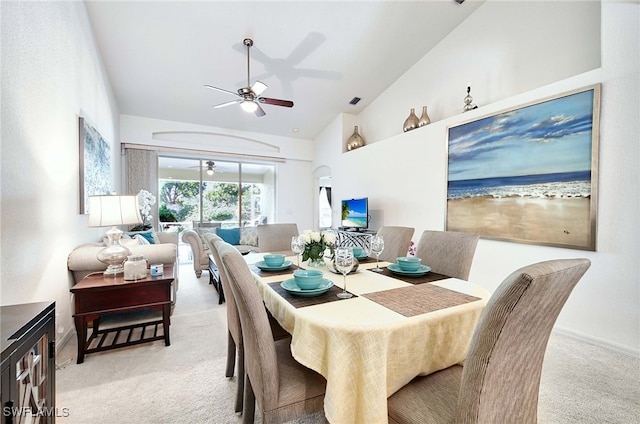 carpeted dining space with high vaulted ceiling and ceiling fan