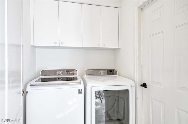 laundry room featuring separate washer and dryer and cabinets