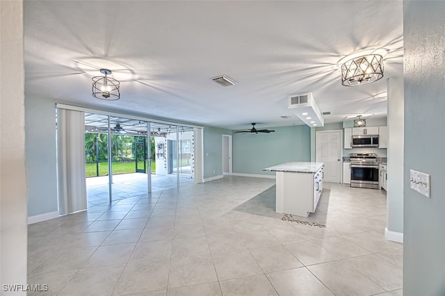 kitchen with ceiling fan with notable chandelier, a wall of windows, white cabinetry, appliances with stainless steel finishes, and a center island