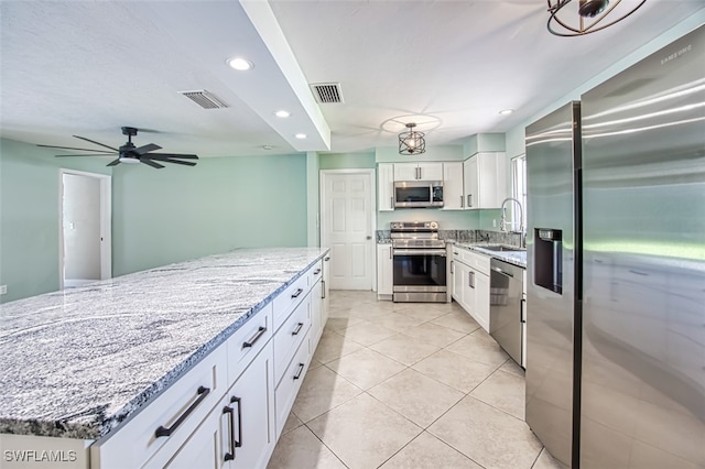 kitchen with light stone counters, ceiling fan, appliances with stainless steel finishes, white cabinets, and light tile patterned flooring