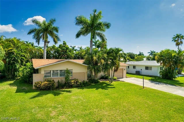 ranch-style house with driveway, brick siding, central AC, and a front yard