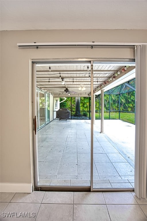 doorway with baseboards, a wealth of natural light, and tile patterned floors