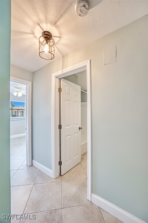 hall with light tile patterned flooring and a textured ceiling