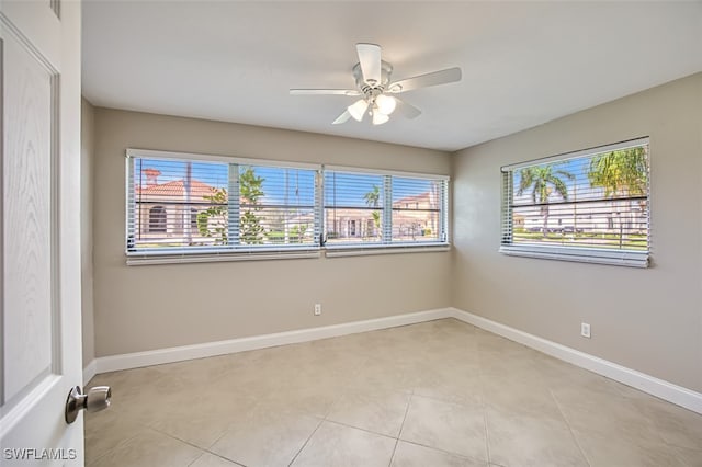 tiled spare room with ceiling fan