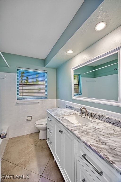 full bathroom featuring shower / bathtub combination, toilet, tile patterned floors, tile walls, and vanity