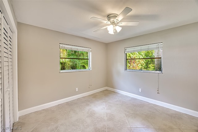 unfurnished room with a ceiling fan, a wealth of natural light, and baseboards