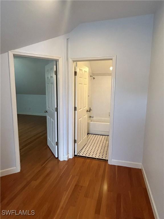 hallway with lofted ceiling, baseboards, and wood finished floors