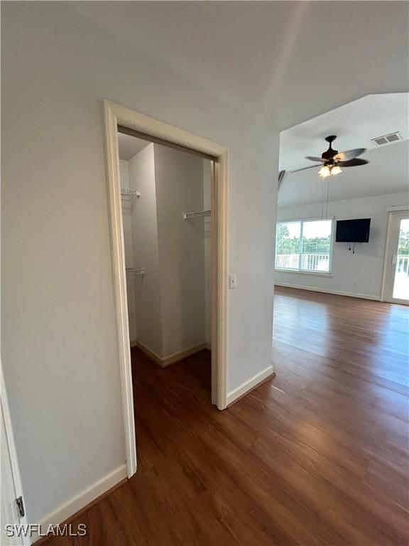 hall with baseboards, visible vents, and wood finished floors