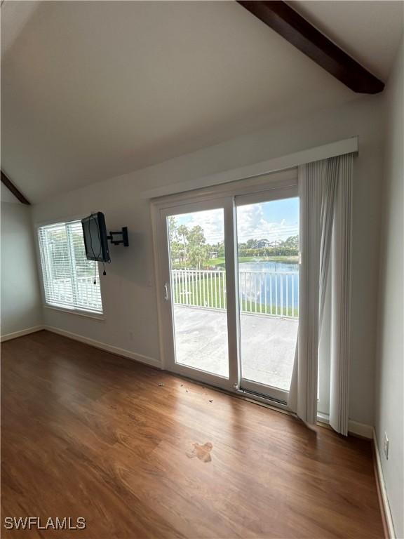 spare room featuring vaulted ceiling with beams and hardwood / wood-style floors