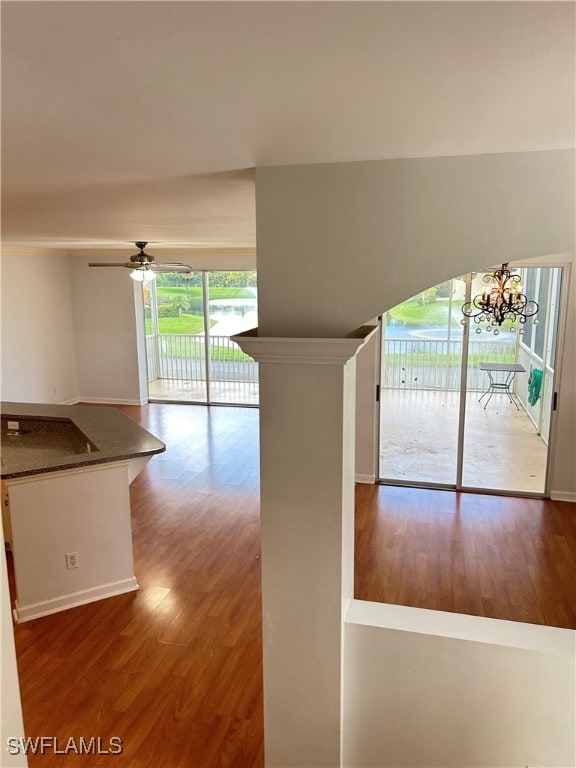 unfurnished living room with hardwood / wood-style floors and ceiling fan with notable chandelier