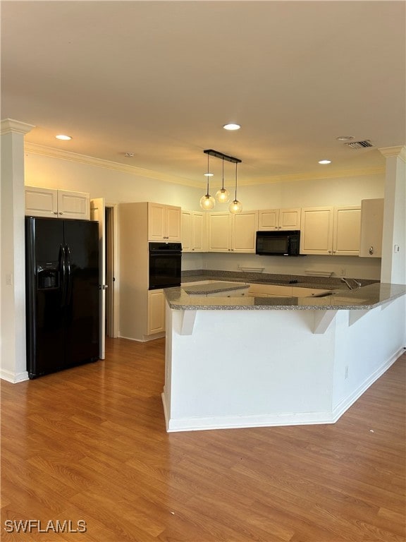 kitchen with light hardwood / wood-style flooring, stone counters, white cabinetry, black appliances, and decorative light fixtures