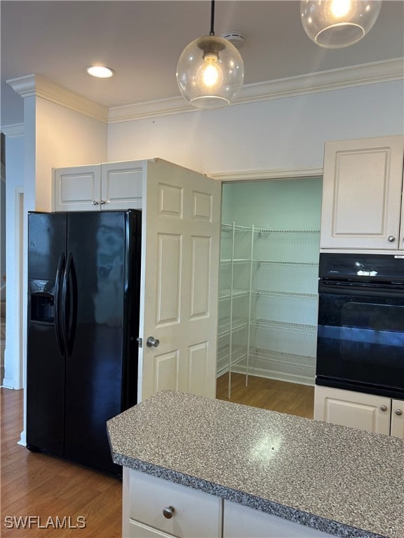 kitchen with black fridge, ornamental molding, white cabinets, hardwood / wood-style floors, and decorative light fixtures