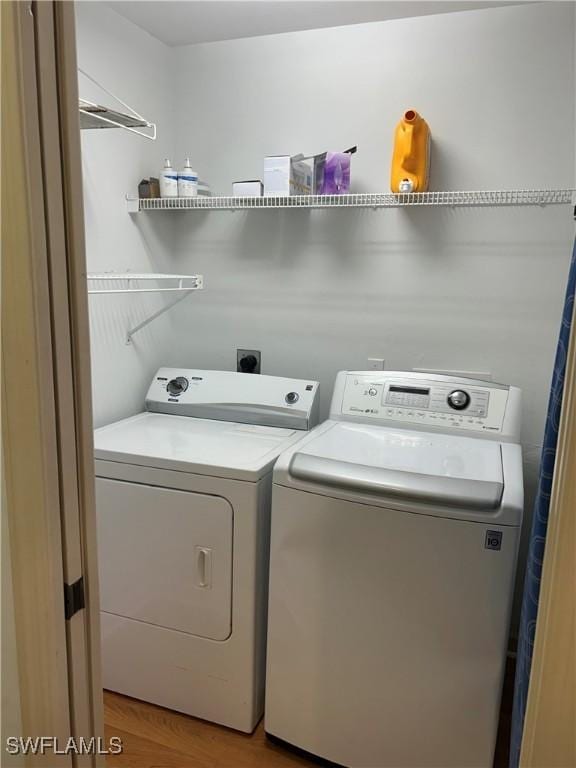 clothes washing area featuring light wood-type flooring, laundry area, and washer and clothes dryer