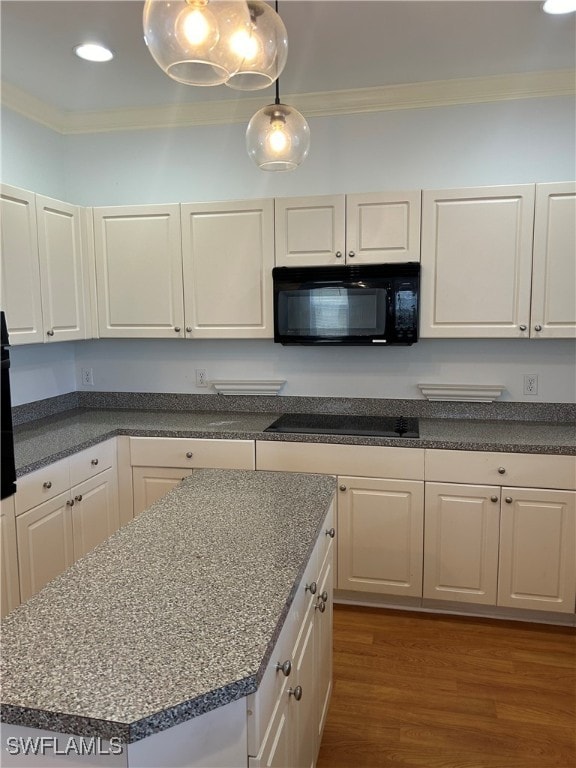 kitchen with black appliances, crown molding, wood-type flooring, and pendant lighting