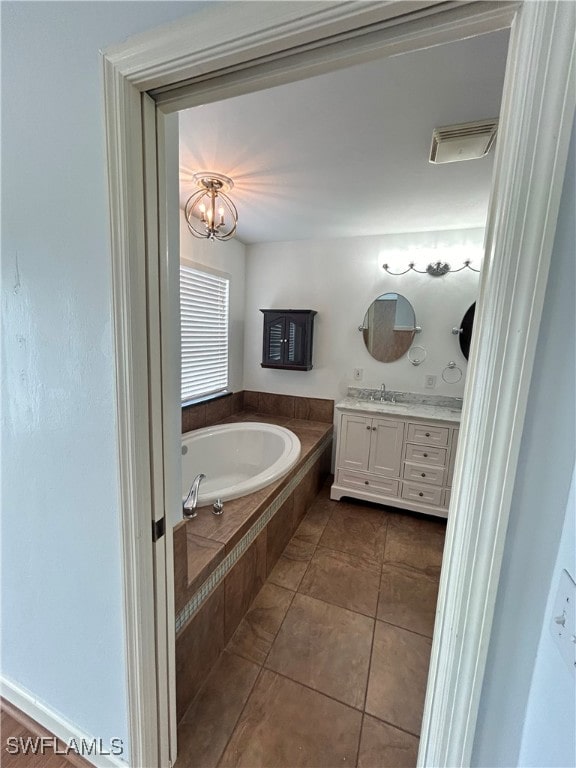 bathroom featuring tiled tub, vanity, and tile patterned flooring