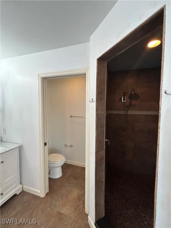 full bathroom with toilet, a stall shower, vanity, and baseboards