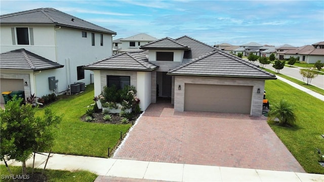 view of front of property featuring a front lawn, decorative driveway, an attached garage, and a residential view