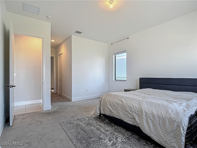 bedroom with baseboards, visible vents, and light colored carpet