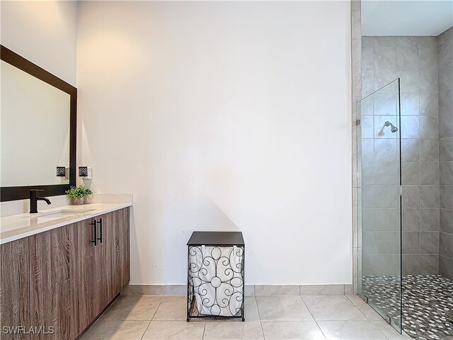 bathroom featuring tile patterned flooring, vanity, and a tile shower