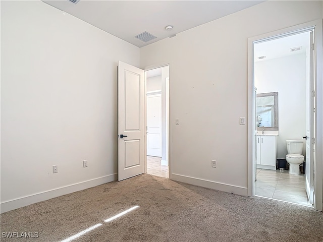 unfurnished bedroom featuring light carpet, connected bathroom, visible vents, and baseboards