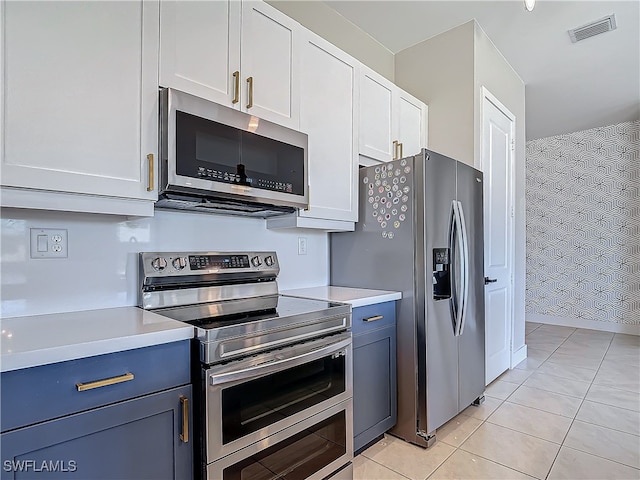 kitchen with blue cabinetry, appliances with stainless steel finishes, light tile patterned floors, and white cabinetry