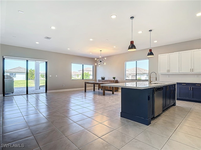 kitchen featuring a kitchen island with sink, pendant lighting, light countertops, and a sink