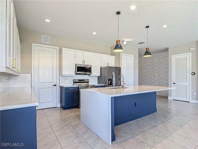 kitchen with a center island with sink, appliances with stainless steel finishes, light countertops, pendant lighting, and a sink