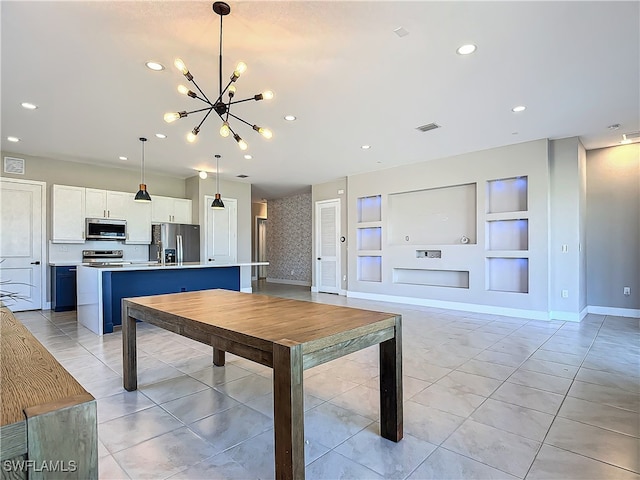 kitchen featuring an island with sink, appliances with stainless steel finishes, hanging light fixtures, light countertops, and white cabinetry