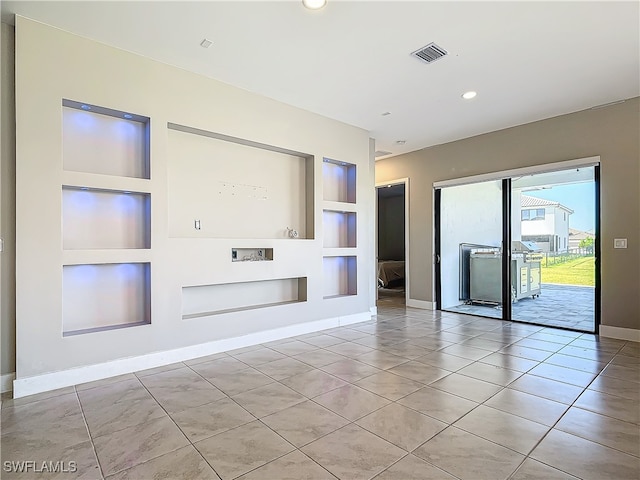 unfurnished living room with built in shelves, visible vents, baseboards, and light tile patterned floors