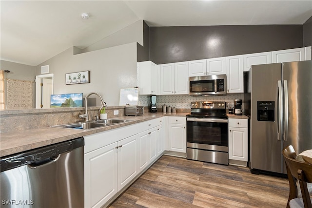 kitchen with tasteful backsplash, appliances with stainless steel finishes, hardwood / wood-style flooring, sink, and kitchen peninsula