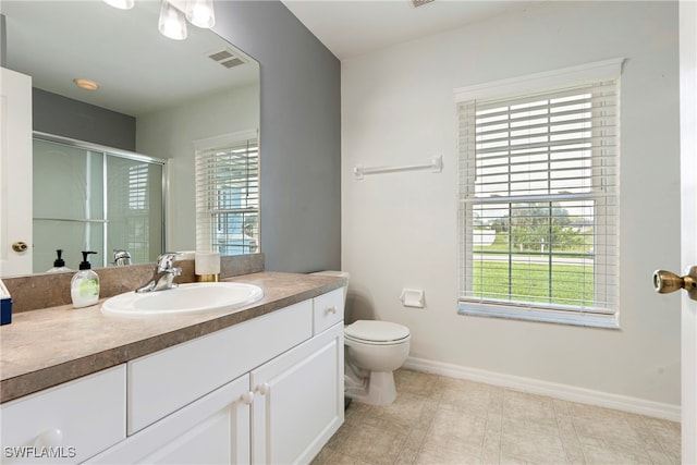 bathroom with vanity, a wealth of natural light, toilet, and tile patterned flooring